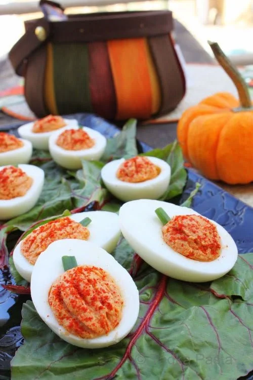 Colorful assortment of Halloween deviled eggs designed as pumpkins for fall festivities.