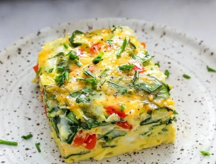 Cheesy protein-packed egg frittata served on a plate with fresh herbs