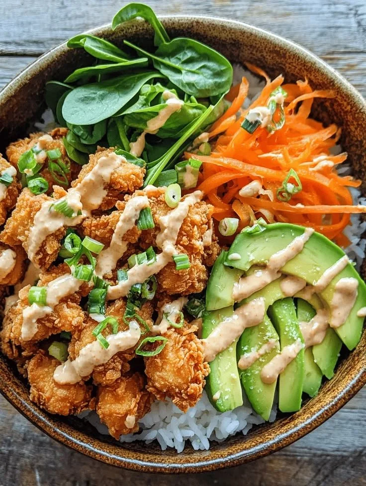 A delicious Bang Bang Chicken bowl topped with fresh vegetables and sauce.