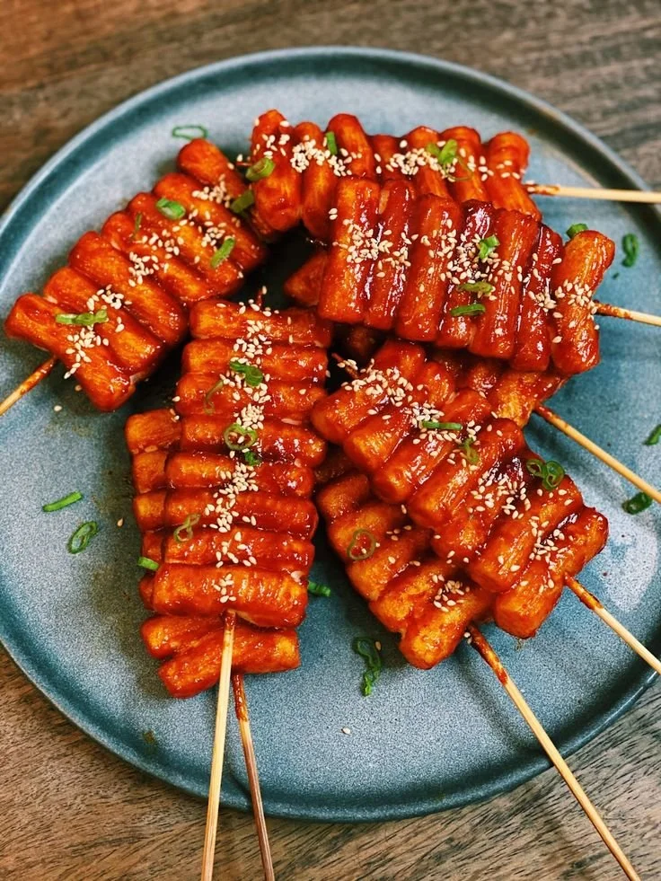 Korean spicy rice cake skewers featuring vibrant, spicy sauce on a skewer.