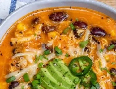 Bowl of low fat chicken enchilada soup with ingredients on display