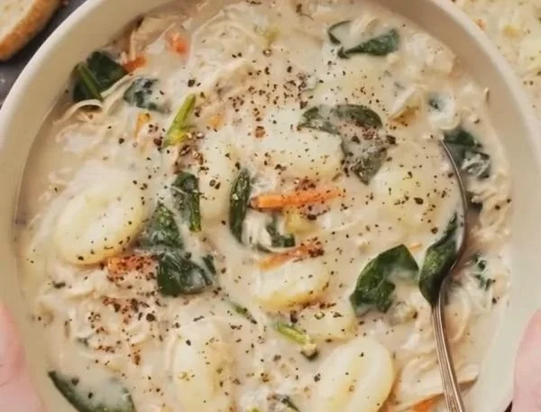 Bowl of slow cooker chicken gnocchi soup with fresh herbs and bread