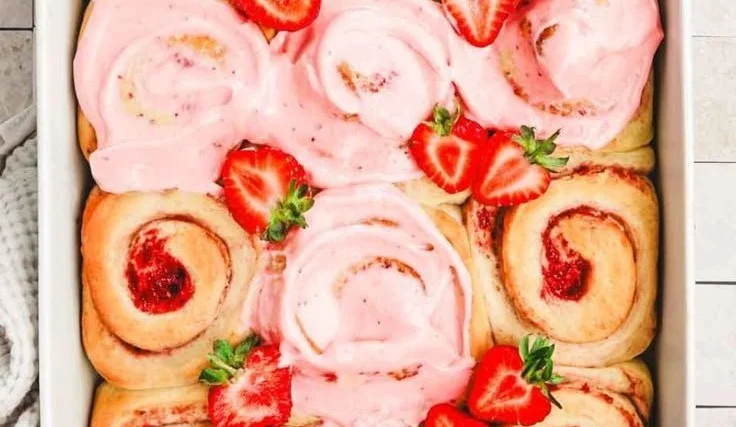 Freshly baked strawberry cinnamon rolls with cream cheese icing on a plate